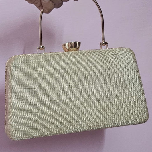 Hand holding a light green handbag against a plain background